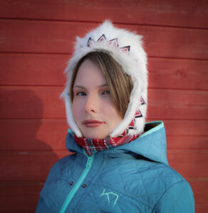 Portrett av en ung kvinne i samisk hvit vinterlue