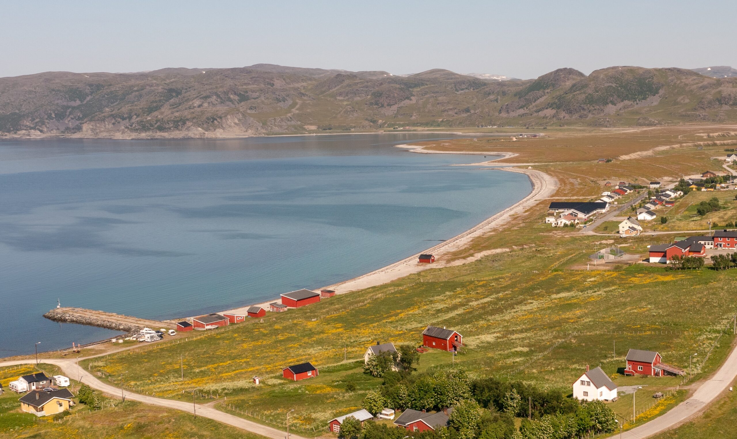 Dronebilde av Kokelv. Nillagården er i høyre nederste hjørne. Oversikt av deler av Kokelvs bebyggelse, inkludert en rekke røde naust, skolen og Kokelv bo og omsorgssenter