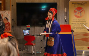 a Sámi woman in traditional clothing receiving a gift.